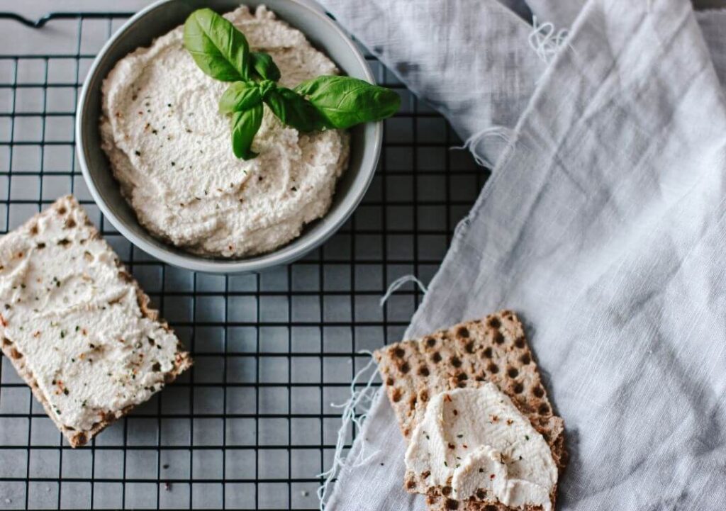 Eine Schüssel mit selbstgemachtem veganen Frsichkäse und einem Knäckebrot