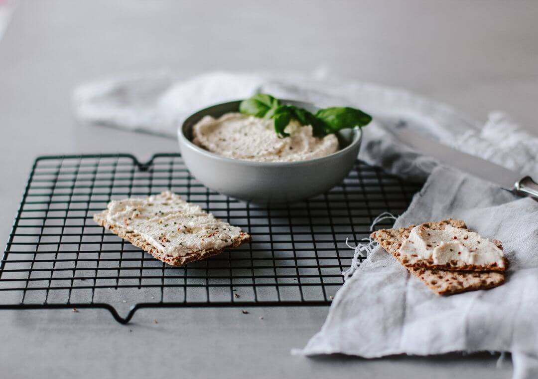 Eine Schüssel mit selbstgemachtem veganen Frsichkäse und einem Knäckebrot