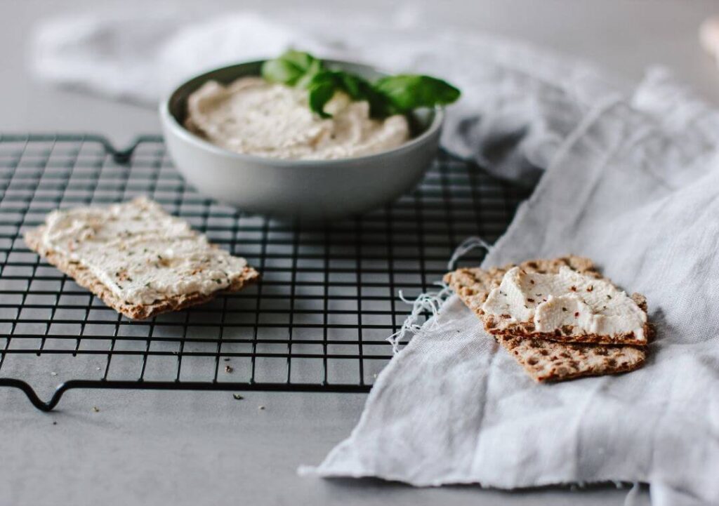 Eine Schüssel mit selbstgemachtem veganen Frsichkäse und einem Knäckebrot